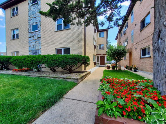 Front view of a multi-story brick apartment building with a stone accent wall.
