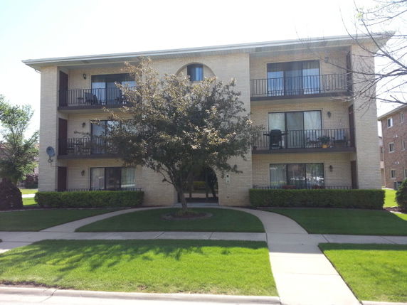 Front view of a three-story apartment building with balconies.