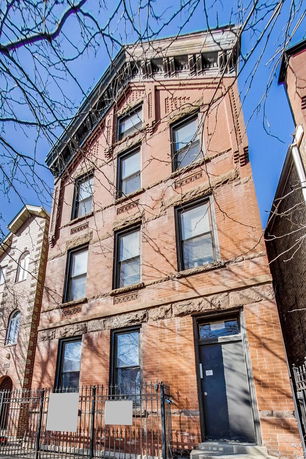 Front view of a multi-story brick building with a sloped roof.