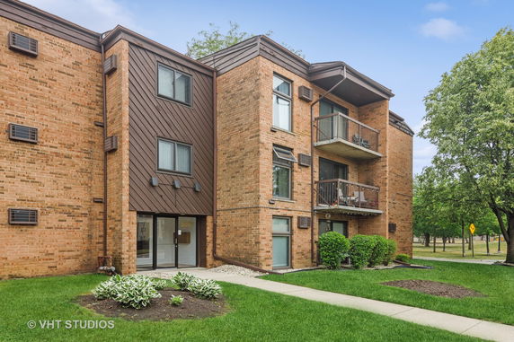 Front view of a multi-story brick apartment building with balconies.