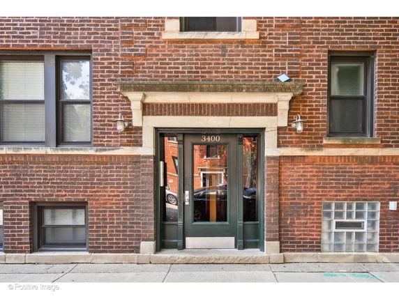 Front view of a brick building entrance with windows and a doorway.