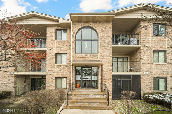 Front view of a multi-story brick apartment building with balconies.