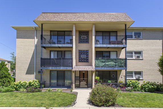 Front view of a three-story brick apartment building with balconies.