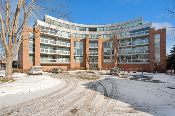 Front view of a multi-story building with large glass windows and a brick facade.