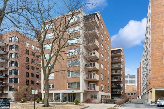 Front view of a multi-story apartment building with balconies and brick exterior.