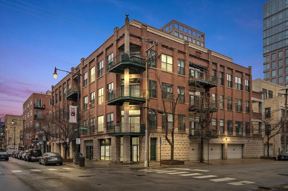 Front view of a multi-story brick building on a street corner.