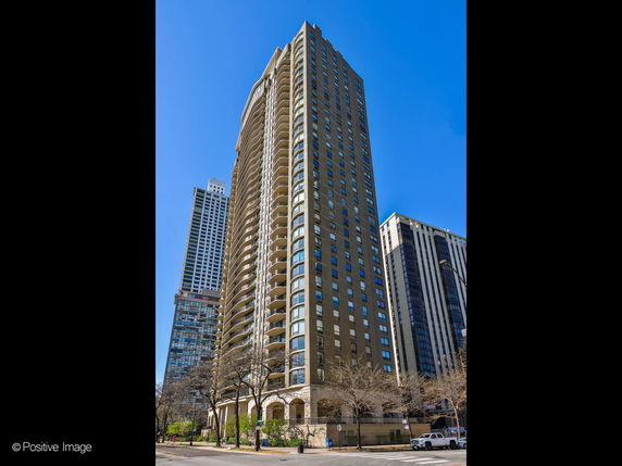 Front view of a tall residential building with multiple balconies.