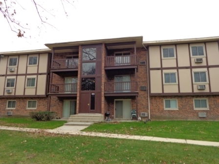 Front view of a multi-story apartment building with a central entrance and balconies.