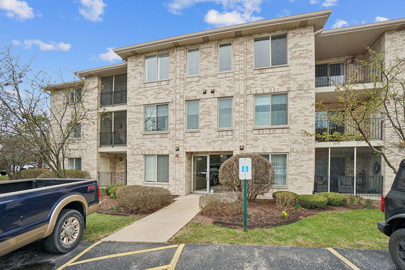 Front view of a multi-story apartment building with brick exterior and balconies.