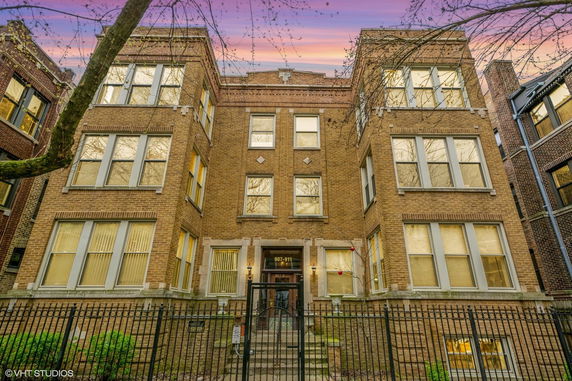 Front view of a multi-story brick building with a gated entrance.