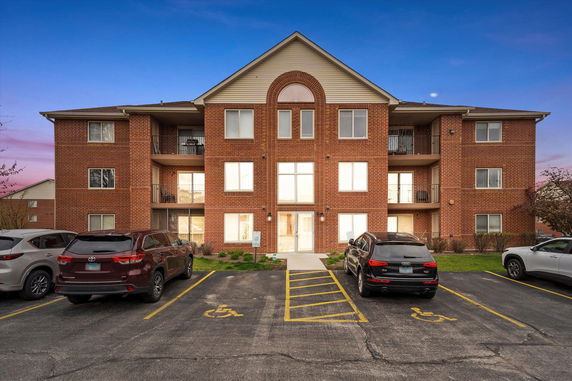 Front view of a brick apartment building with parking spaces in front.