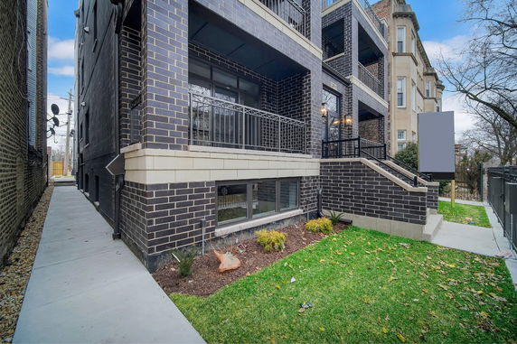 Side view of a multi-story building with balconies and a concrete walkway.