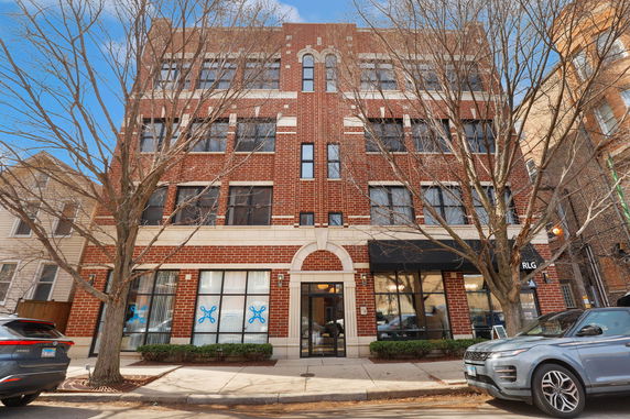Front view of a multi-story brick building with large windows.
