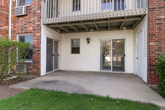 Outdoor view of a residential building with a small patio and balcony above.