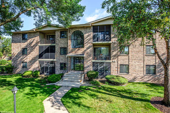 Front view of a multi-story apartment building with brick exterior and balconies.