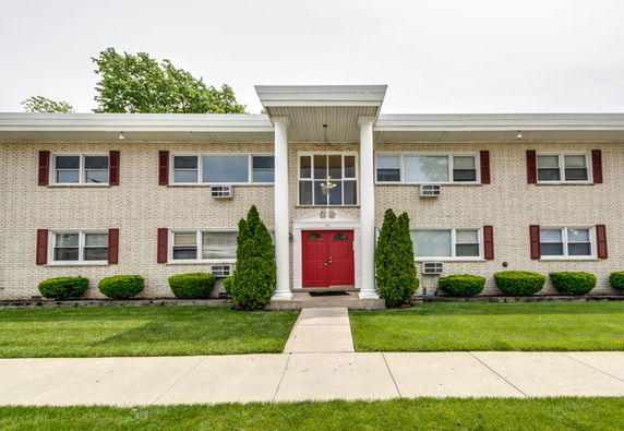 Front view of a two-story building with a central entrance featuring double red doors and white columns.