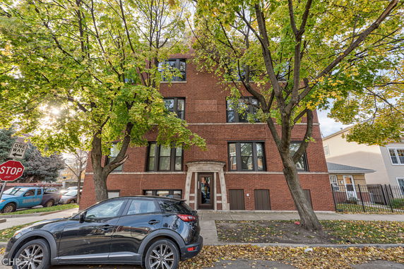 Front view of a multi-story brick apartment building with large windows.