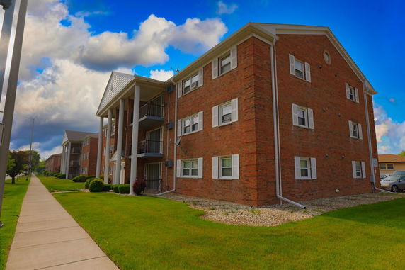 Front view of a multi-story brick apartment building with balconies and columns.