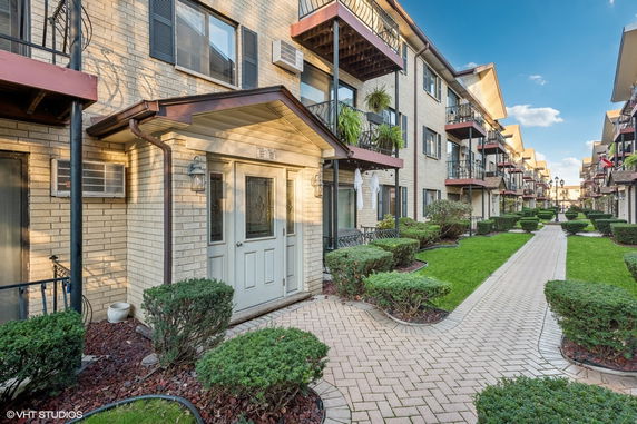 Front view of a residential building with balconies and a landscaped walkway.