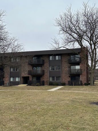 Front view of a three-story apartment building with balconies and brick exterior.