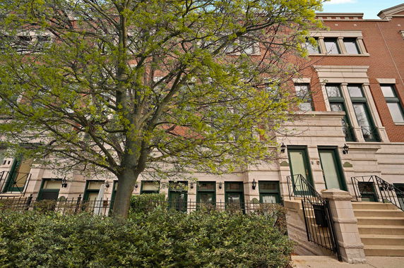 Front view of a multi-story brick building with outdoor stairs and large windows.