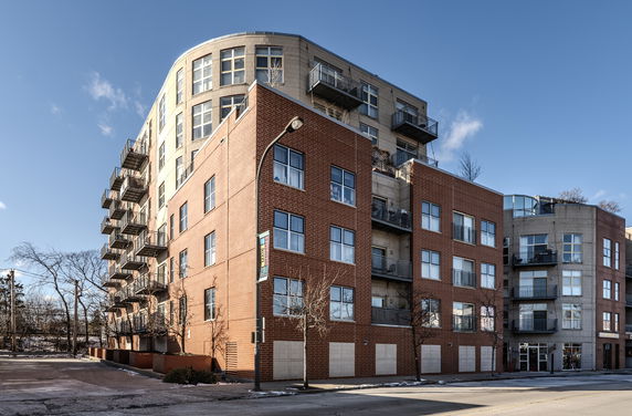 Front view of a multi-story building with brick and concrete facade, featuring balconies on each level.