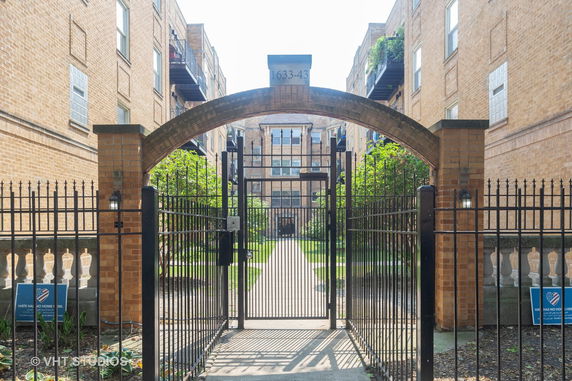 Front view of a multi-story brick building with a gated entrance.