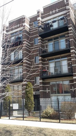 Front view of a multi-story brick residential building with balconies.
