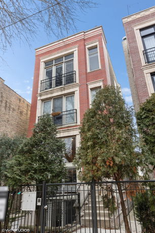 Front view of a multi-story brick building with balconies and large windows.