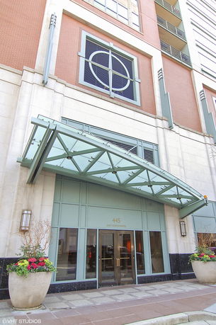 Front view of a building entrance with a glass awning and decorative elements.
