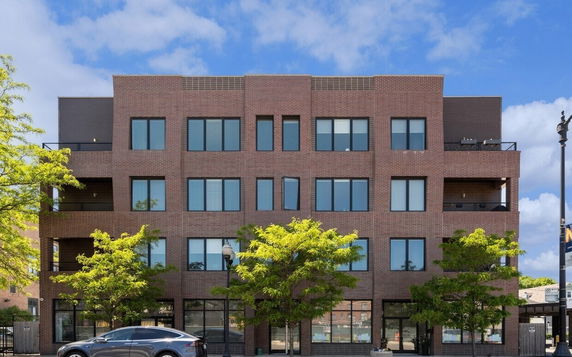 Front view of a multi-story brick building with large windows and balconies.