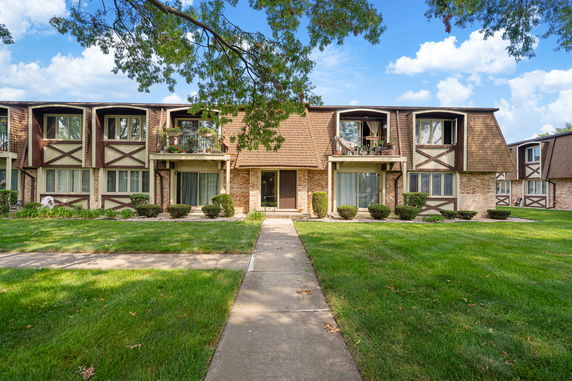 Front view of a multi-story residential building with balconies and sloped shingle roof.