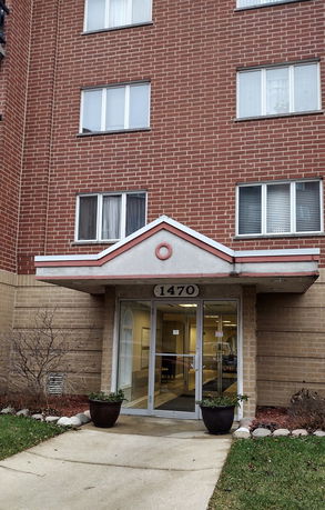 Front view of a multi-story brick apartment building with an entrance canopy.