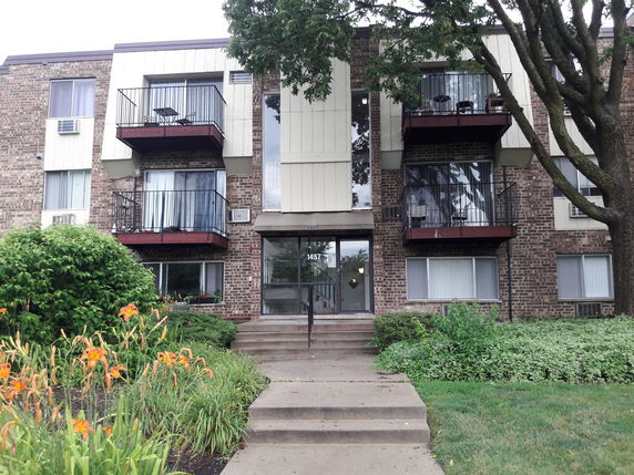 Front view of a three-story brick apartment building with balconies.