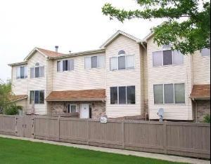 Front view of a two-story house with beige siding and brown roof shingles.