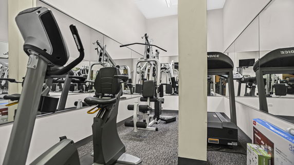 Indoor gym area with exercise equipment including a stationary bike, treadmill, and weight machines.
