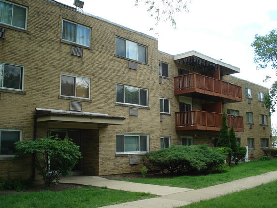 Front view of a multi-story apartment building with balconies and brick exterior.
