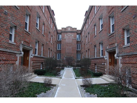 Front view of a multi-story brick apartment building with a courtyard.