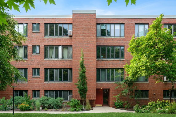 Front view of a three-story brick apartment building with multiple windows and a central entrance.