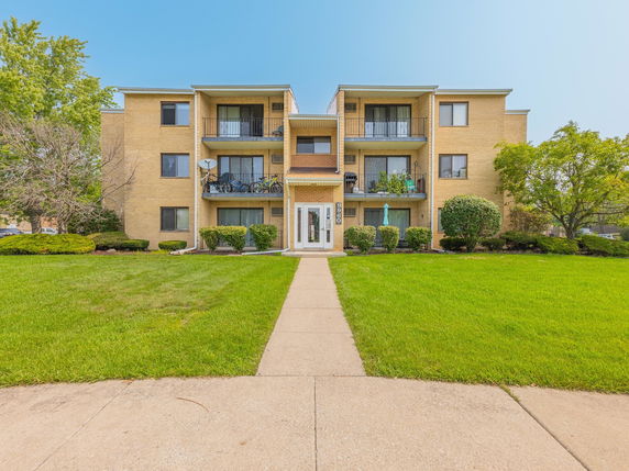 Front view of a three-story apartment building with balconies.