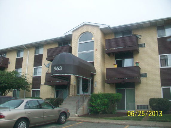 Front view of a multi-story apartment building with balconies and an entrance canopy.