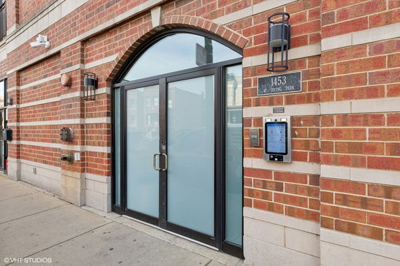 Front view of a brick building entrance with glass doors.
