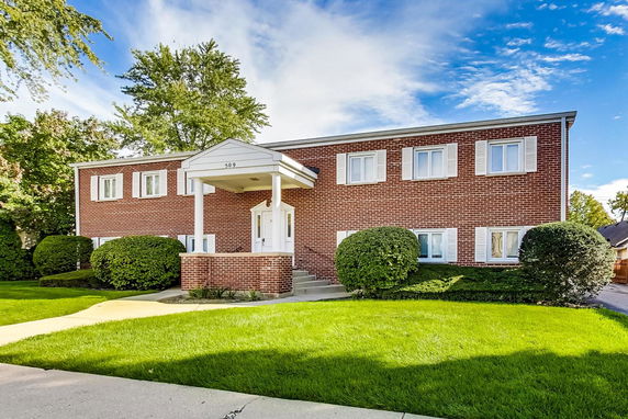 Front view of a two-story brick house with a column-supported entrance.