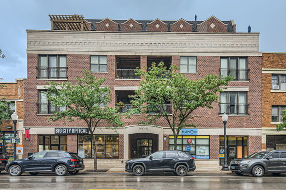 Front view of a multi-story brick building with commercial spaces on the ground floor.