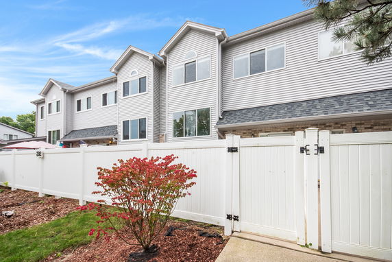 Front view of a two-story residential building with a white fence.