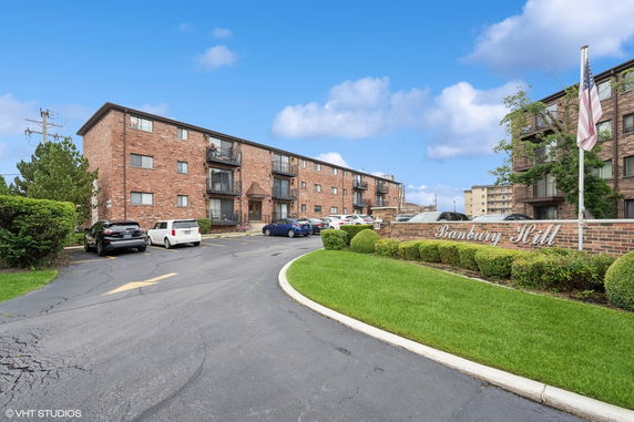 Front view of a multi-story brick apartment building with balconies.