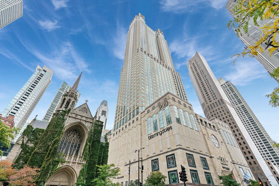 Front view of a tall building in a cityscape with a historic church in the foreground.