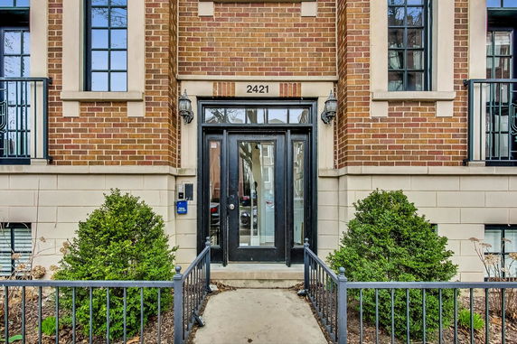 Front view of a brick building entrance with windows and number 2421 above the door.