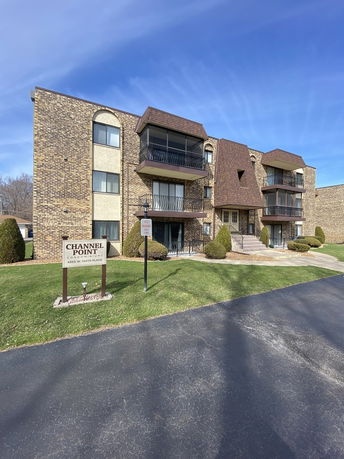 Front view of a condominium building with multiple balconies and a brick exterior.