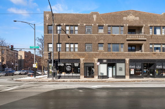 Front view of a three-story brick building with shops on the ground floor.